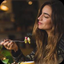 Ein lebendiges, gesundes Buffet mit einem Salat in einer Schüssel, umgeben von Nüssen, Samen, Brokkoli, Tomaten, Karotten, Blaubeeren, Avocado, Äpfeln, Zitrusfrüchten, Gurken und Olivenöl auf einem rustikalen Holztisch.