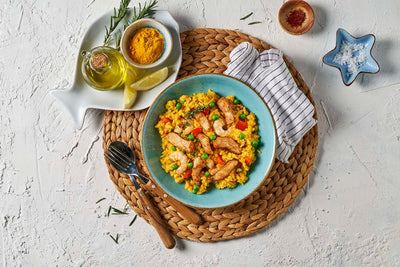 Eine farbenfrohe Paella-Schüssel mit Meeresfrüchten und Gemüse, ergänzt durch Gewürze, Öl und Besteck auf einem gewebten Tischset. Als Teil von HOFMANNs Reis-Kreationen aus Hofmanns Shop verkörpert sie mit jedem Bissen die Essenz der internationalen Küche.