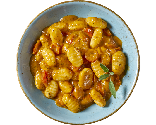 Eine Schüssel Gnocchi alla Roma von Hofmanns Shop in einer würzigen Tomaten-Basilikumsoße, garniert mit einem Zweig frischer Kräuter.