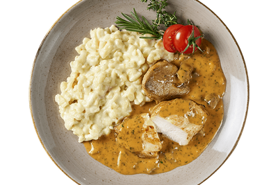 Ein Filetteller aus Hofmanns Shop mit cremigen Käsespätzle, Hähnchenbrustfiletscheiben in brauner Sauce, Kirschtomaten und Kräutern zum Garnieren.