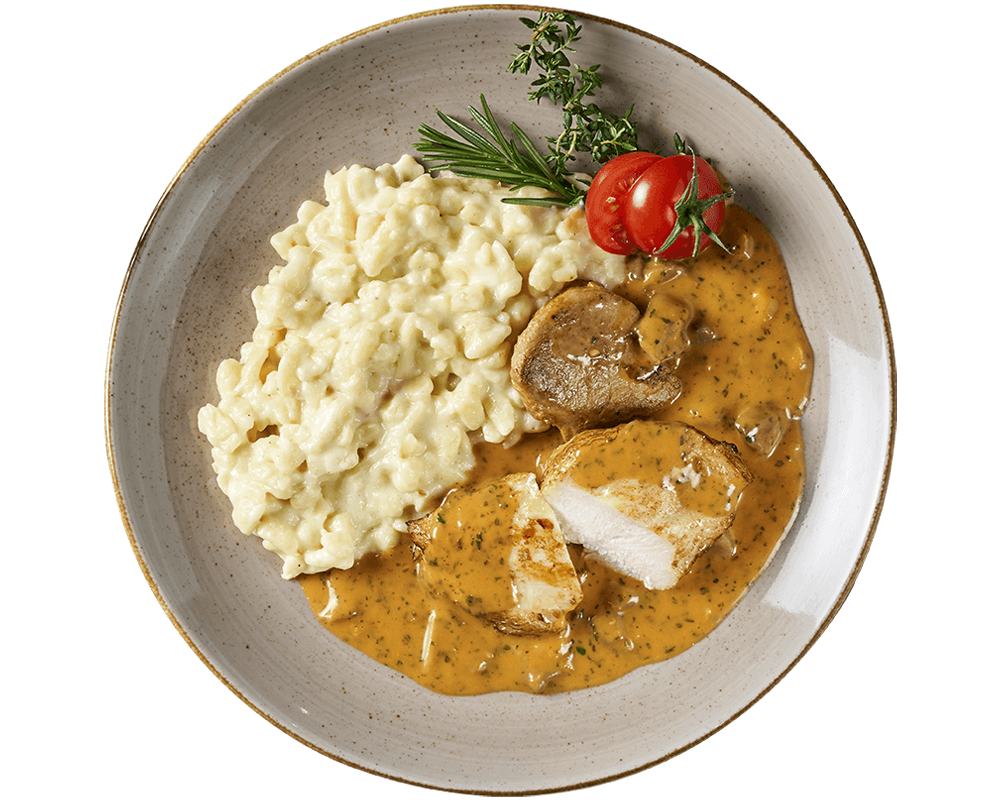 Ein Filetteller aus Hofmanns Shop mit cremigen Käsespätzle, Hähnchenbrustfiletscheiben in brauner Sauce, Kirschtomaten und Kräutern zum Garnieren.
