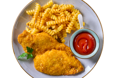 Teller mit Hofmanns Shop Hähnchenschnitzel in Cornflakespanade, Pommes frites, Ketchup, Petersilie.