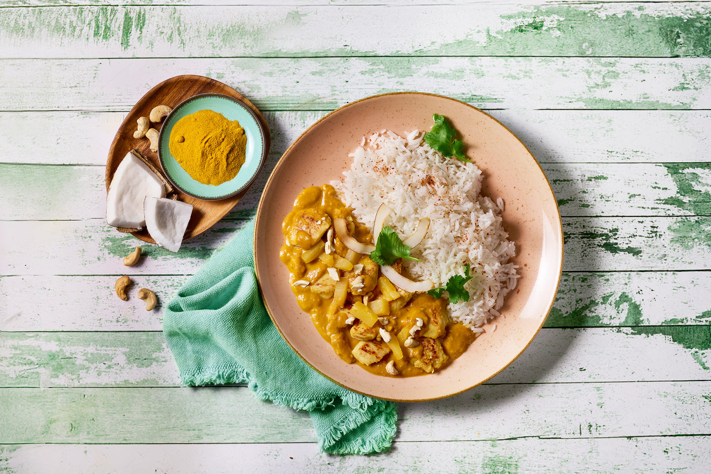 Kokoshuhn von Hofmanns Shop: Curry mit Basmati-Reis, Kokosnuss-Garnitur, daneben Kurkuma und Cashews.