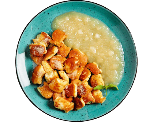 Goldener Kaiserschmarrn mit Apfelkompott von Hofmanns Shop, serviert auf einem türkisfarbenen Teller.