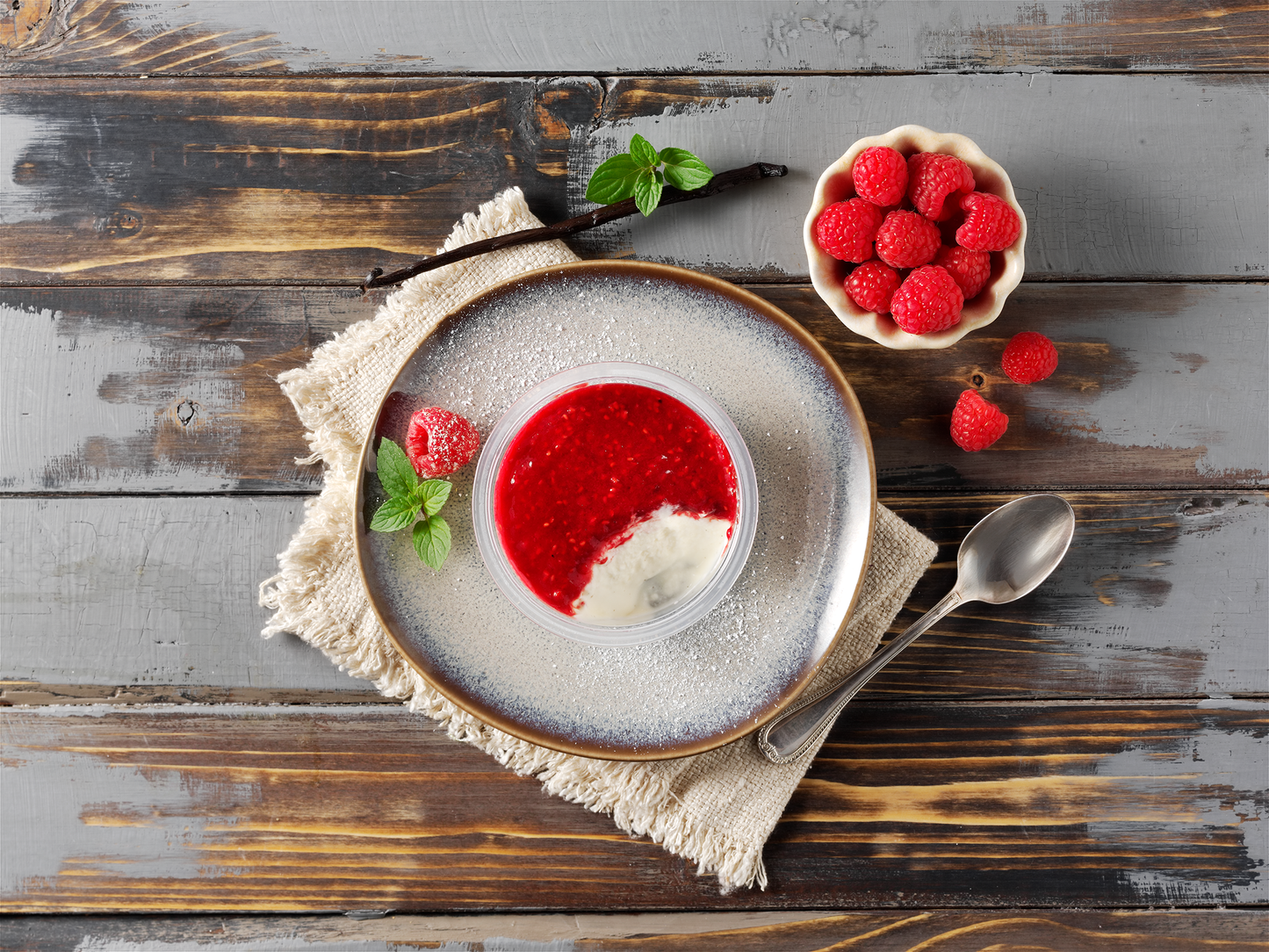 Bayrische Creme mit Himbeere von Hofmanns Shop, mit Sahne und Minze, serviert auf rustikalem Tisch.