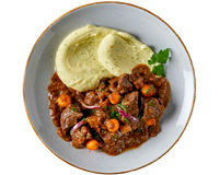 Ein Teller mit Boeuf à la Bourguignon von Hofmanns Shop, cremigem Kartoffelstampf, einem Eintopf aus zartem Rindfleisch mit Karotten und Zwiebeln, alles garniert mit Petersilie und liebevoll mit Rotwein geschmort für mehr Geschmackstiefe.