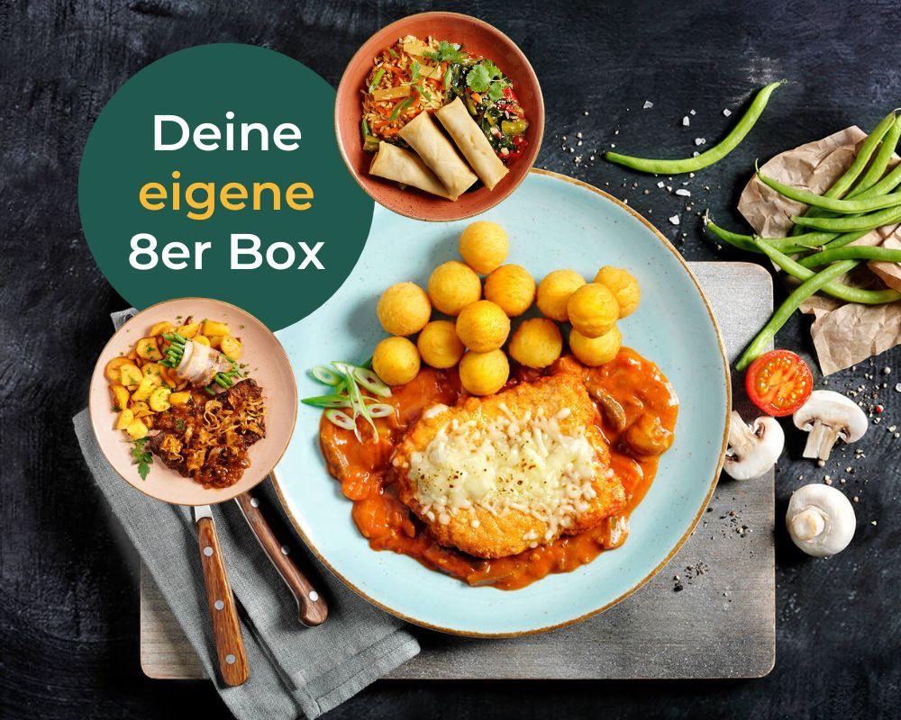 Teller mit Hähnchen mit Sauce, Kartoffelbällchen, Gemüse und Frühlingsrollen, begleitet vom Text „Meine eigene Box“ von HOFMANNs.