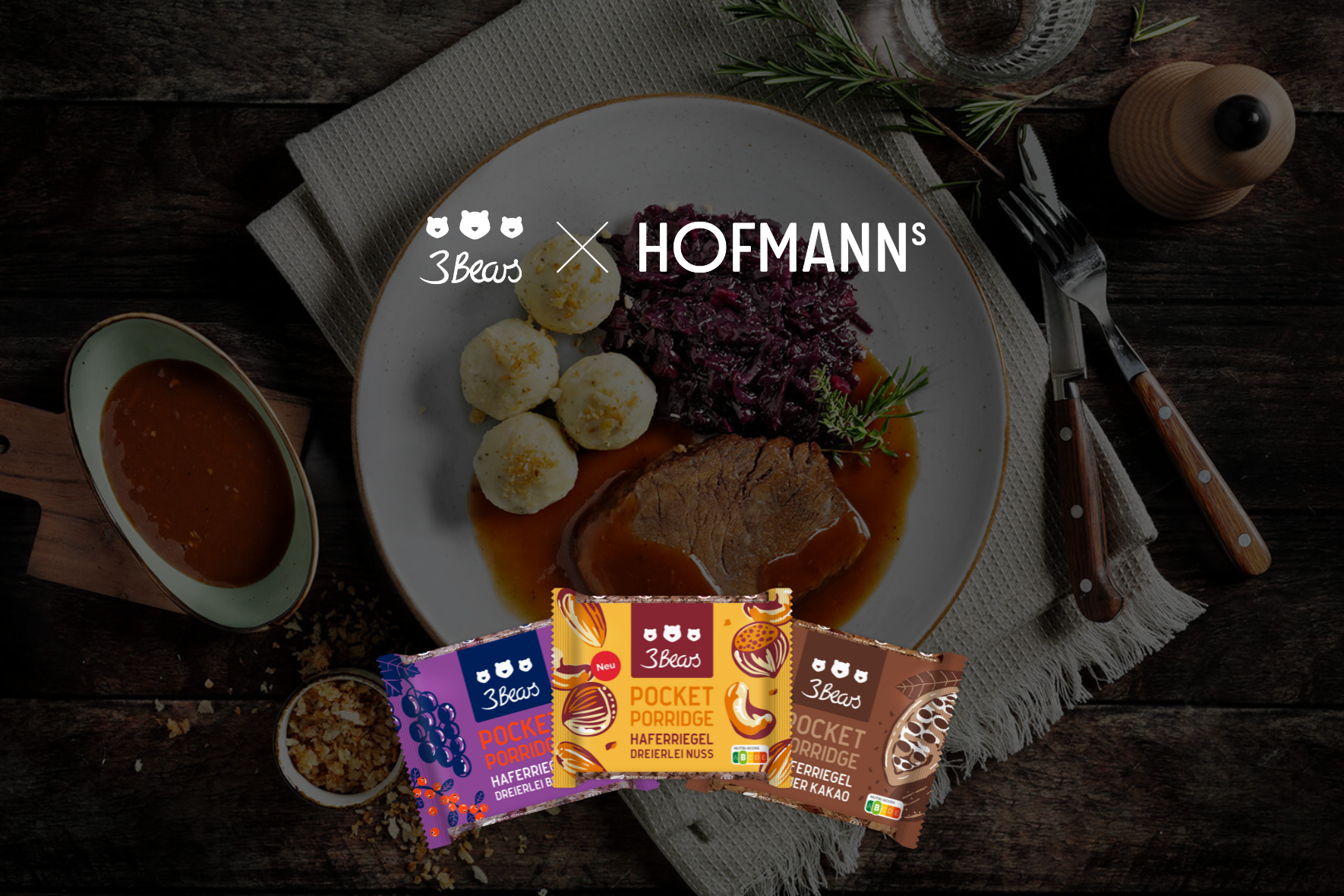 Teller mit Fleisch, Knödeln und Rotkohl, umgeben von Breipackungen und Küchenutensilien.