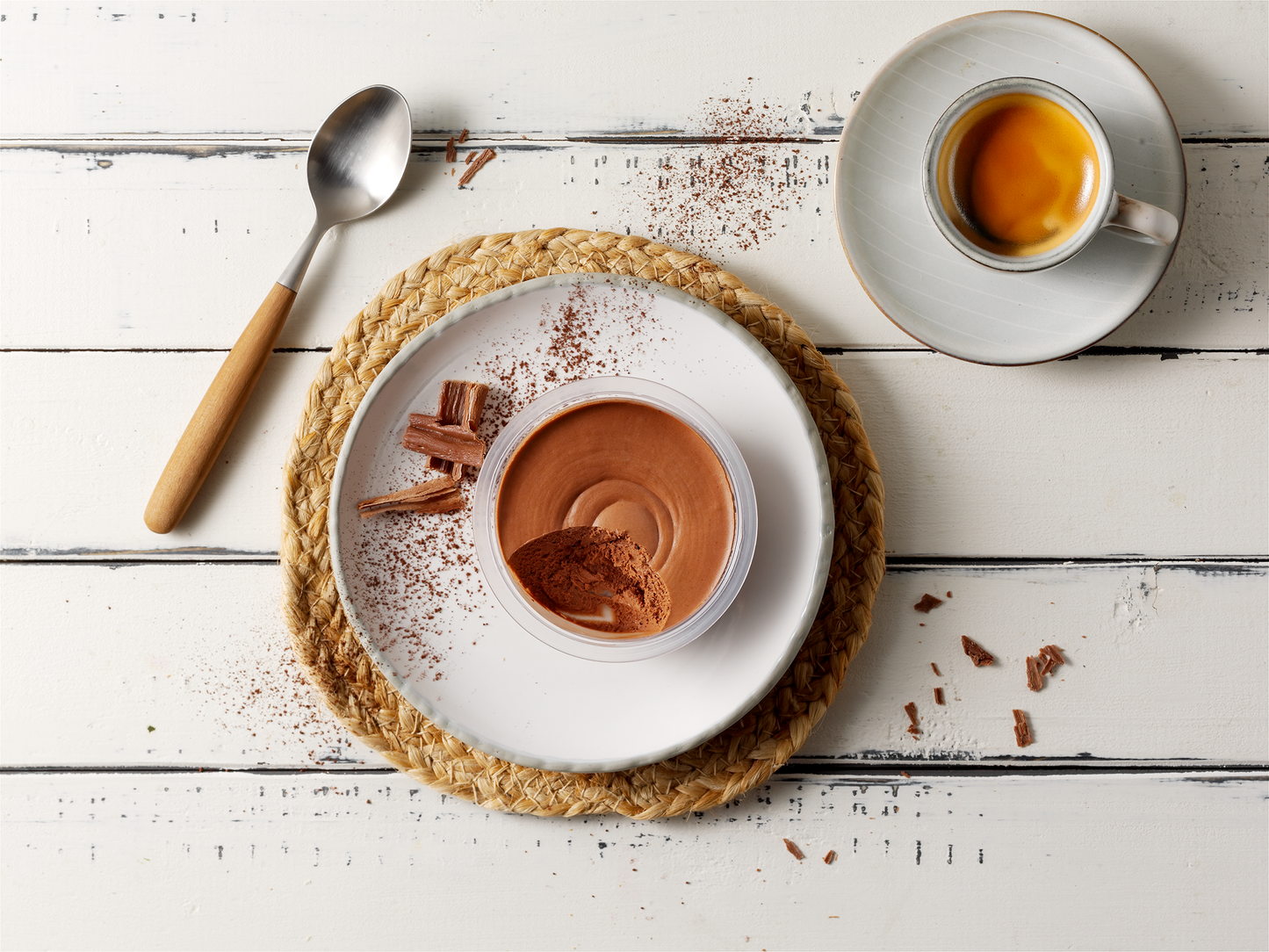 Eine Tasse Espresso und Mousse dunkel von Hofmanns Shop mit Schokoladenraspeln auf einem weißen Tisch.