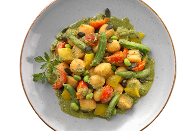 Ein Teller Süßkartoffel-Gnocchi mit Erbsenpesto von Hofmanns Shop, dazu gemischtes Gemüse und garniert mit Petersilie.