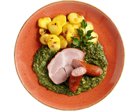 Ein Teller mit HOFMANNs Grünkohl „Norddeutsche Art“, Würstchen, Bratkartoffeln und cremigem Spinat.