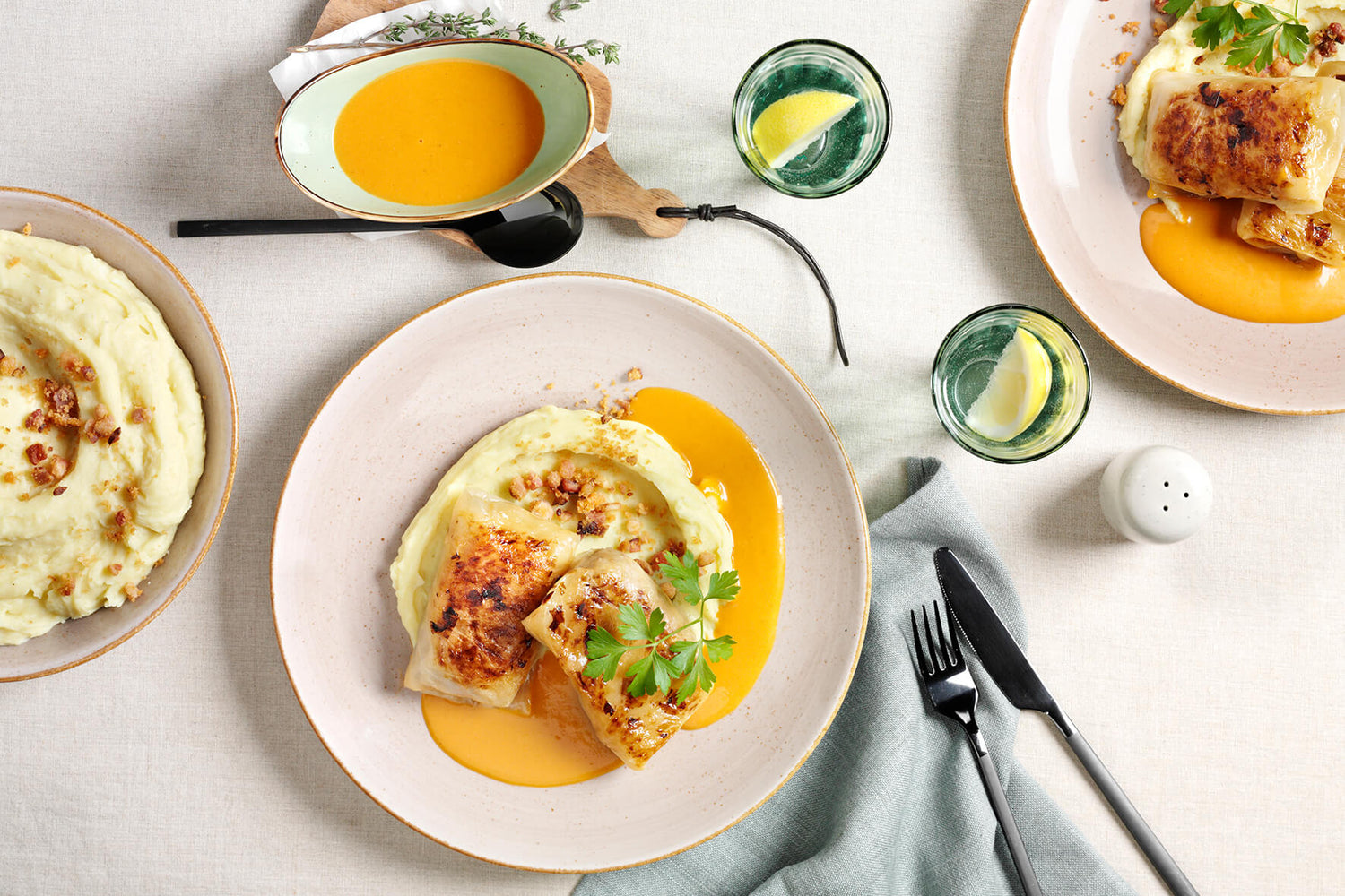 Hofmanns Shop Zwei Kohlrouladen mit Orangensauce, Kräuter. Wasser mit Zitrone serviert.