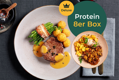 Ein Gourmet-Menü mit Fleisch, grünen Bohnen, Kartoffeln und Soße mit einem Weinglas neben dem Text „Protein Deluxe-Box“ von Hofmanns Shop, perfekt für Kraftsportler auf der Suche nach hochwertigen Protein-Gerichten.